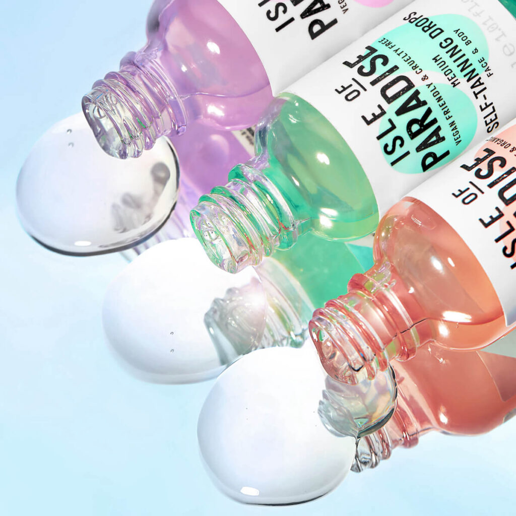 Isle of Paradise Self Tanning Drops in Shade Light, Medium and Dark with product on reflective surface