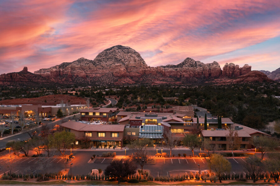 a hotel resort and spa with sedona red rock formations in the background, at sunset